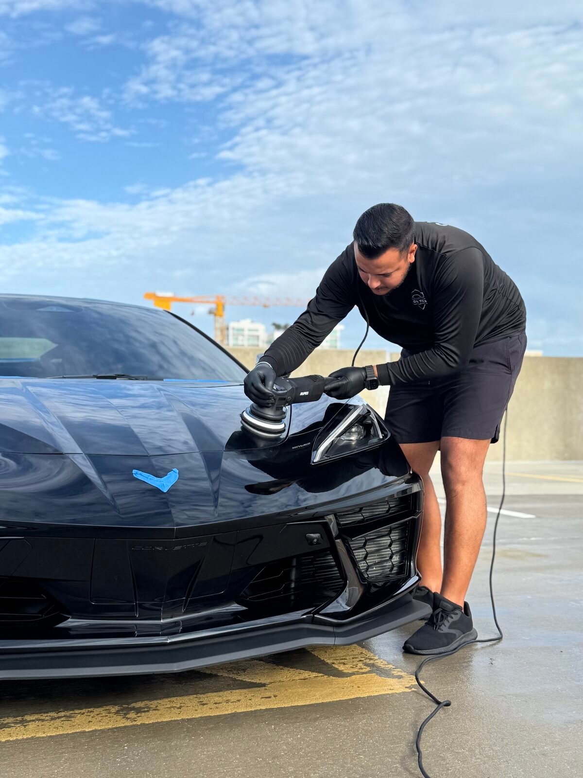Yan performing paint correction on a black Corvette in Sarasota